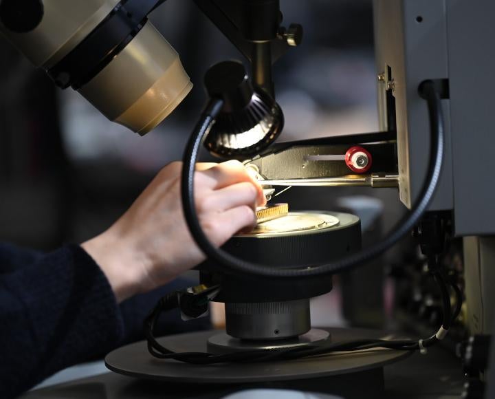 Close-up of hand adjusting a chip under a microscope