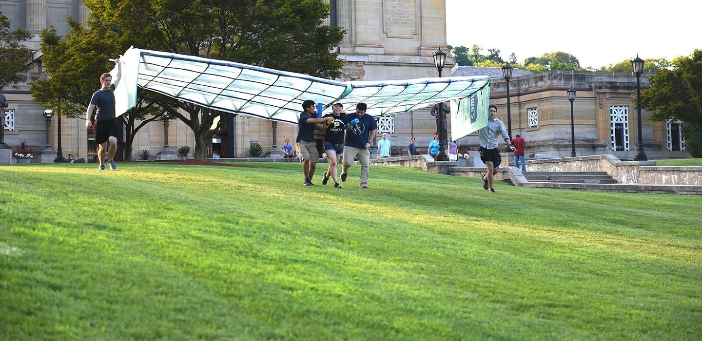 Students run with their glider on a lawn