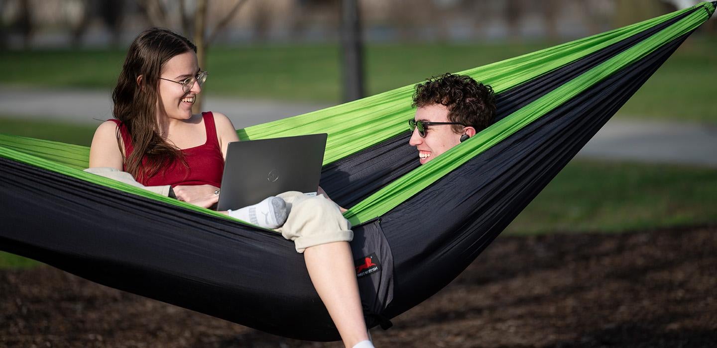 Two students sit in a hammock