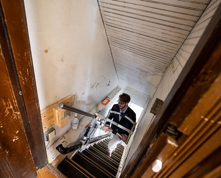 A person climbs stairs with an assistive device