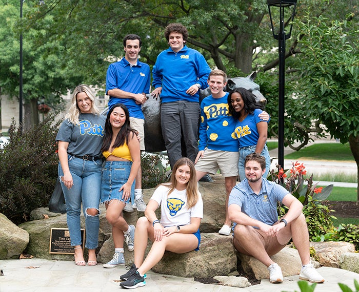 8 students in Pitt gear around a Panther statue