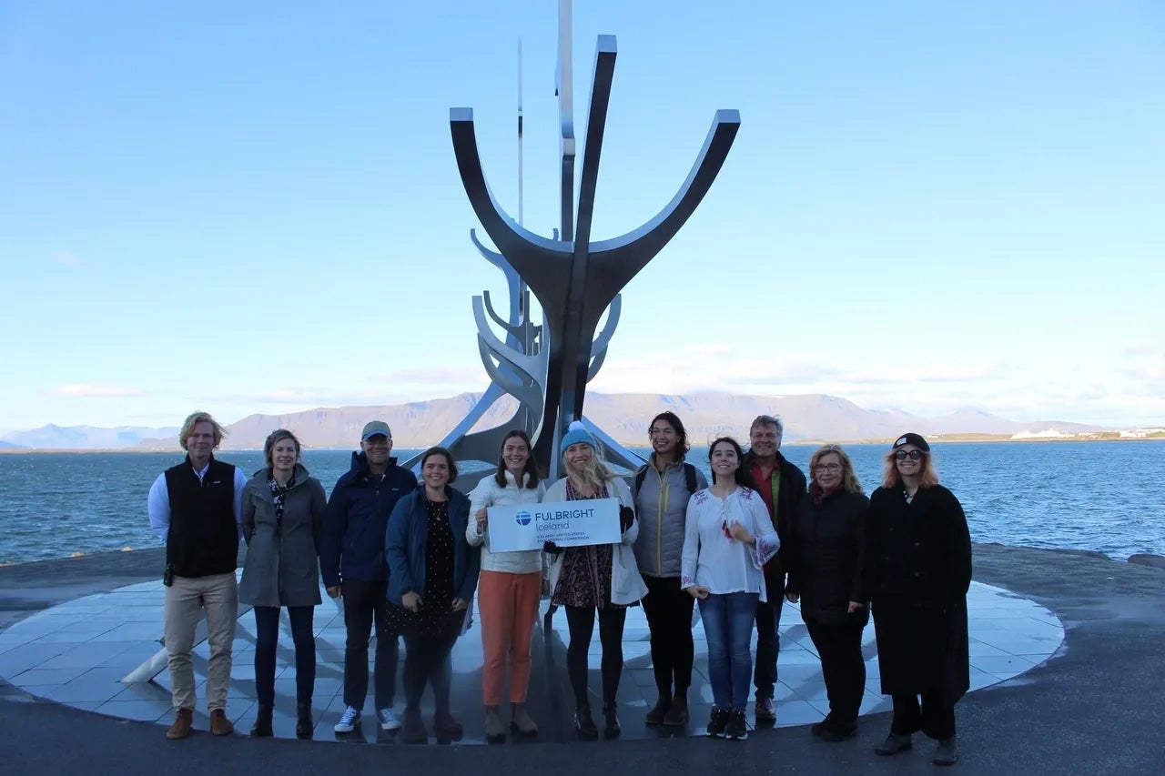 A group of people in front of a statue and the sea in Iceland