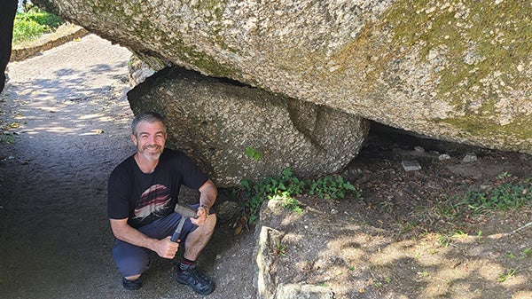 Kerrigan kneels holding a mallet under a rock formation