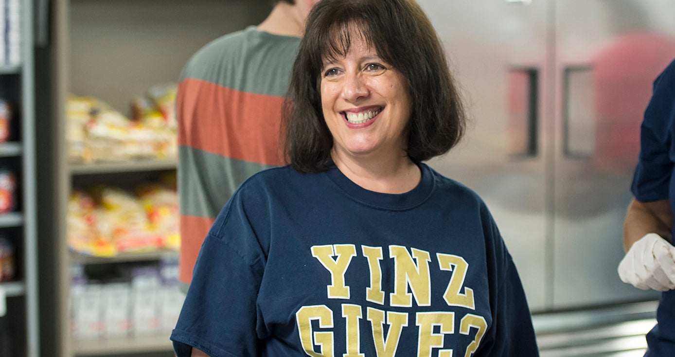 woman in blue and gold "Yinz Give?" shirt