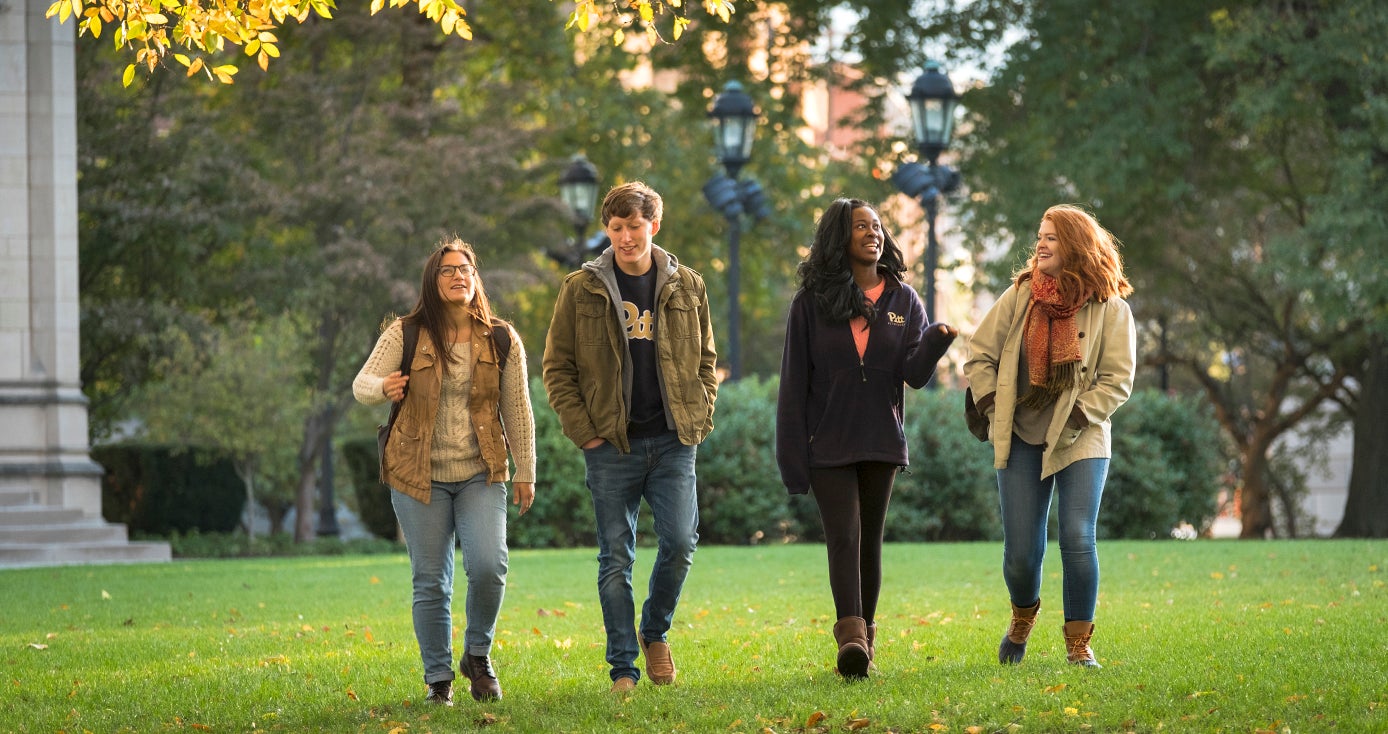 four students walking on Pitt campus in fall