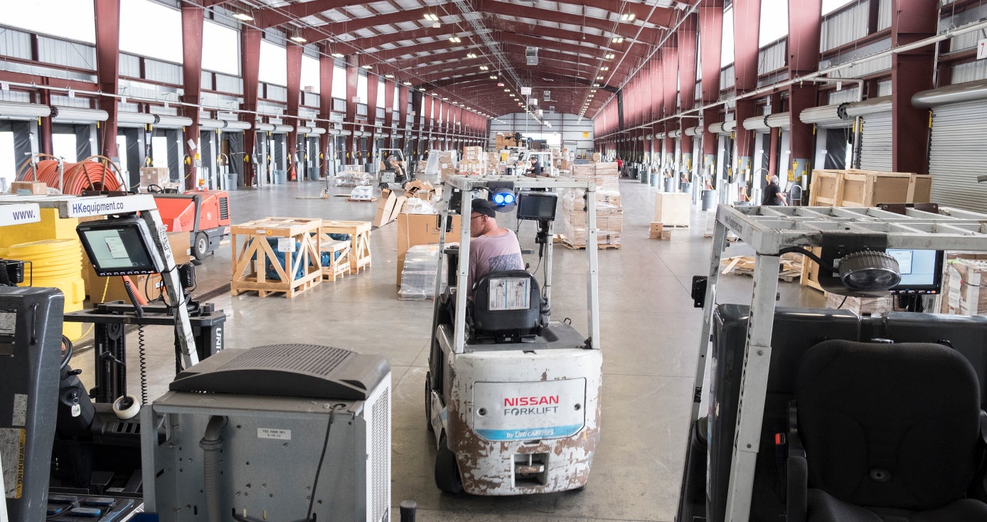 Interior of trucking facility including man operating a forklift