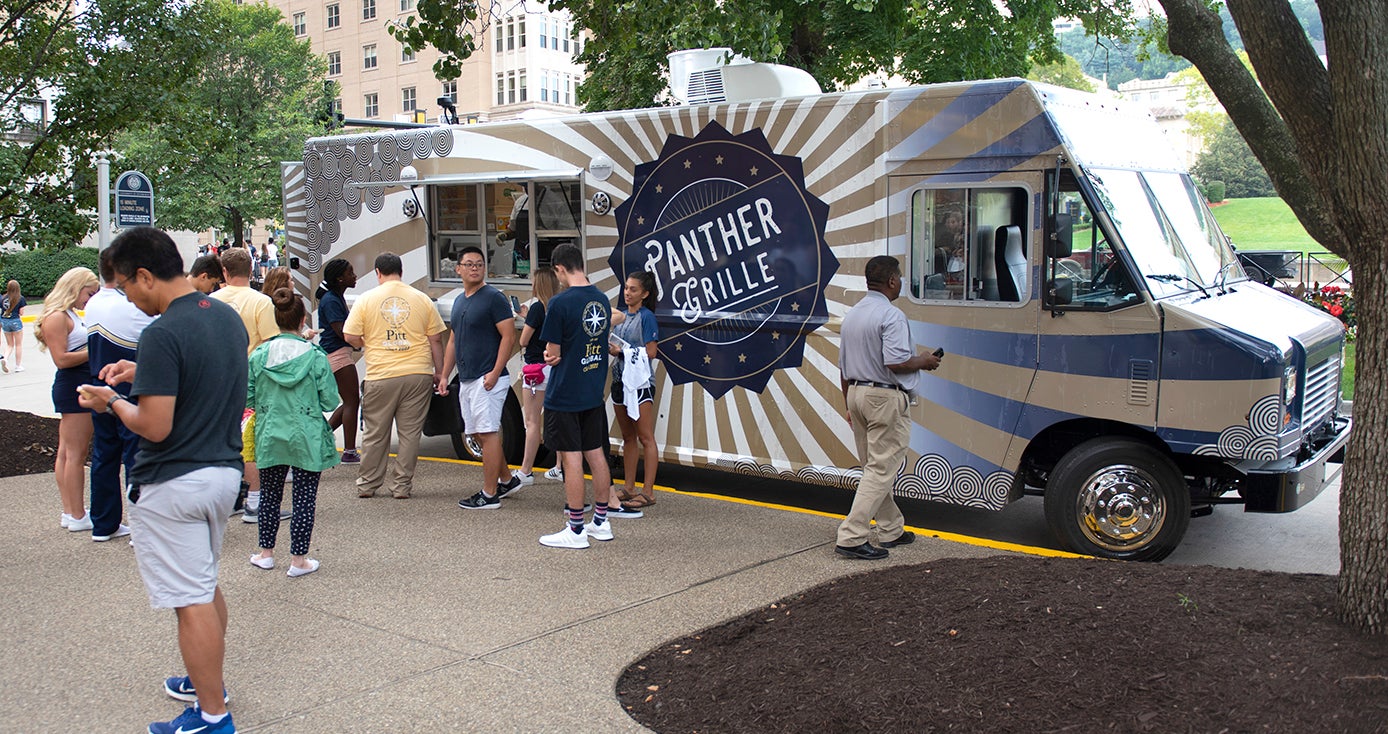 Panther Grille food truck parked among trees with a group of people waiting to order