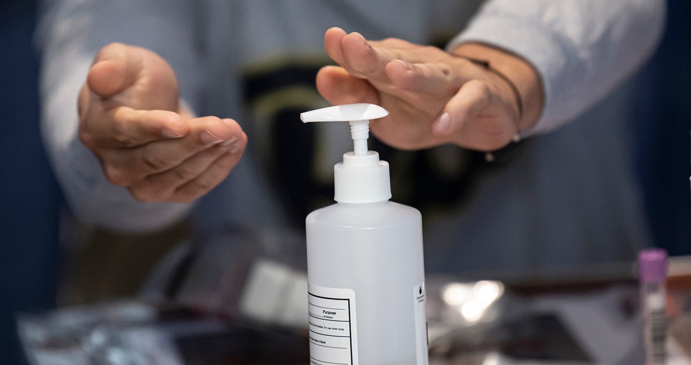 A person uses a hand sanitizer dispenser