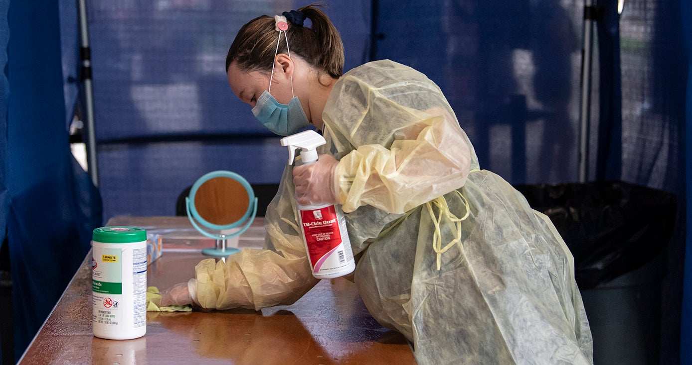 A person in a face mask cleans a testing area