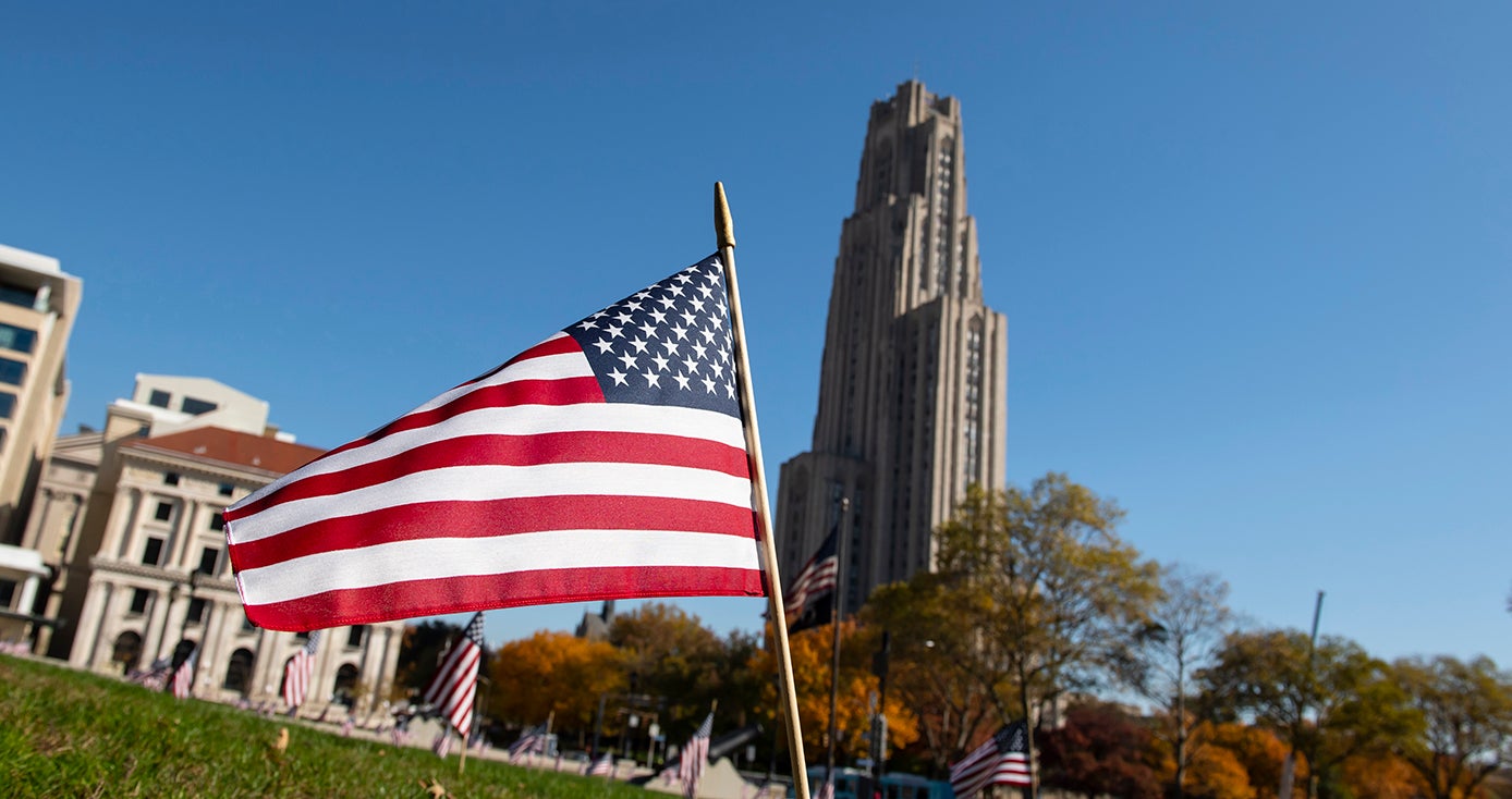 An American flag in the lawn in front of the Cathedral of Learning