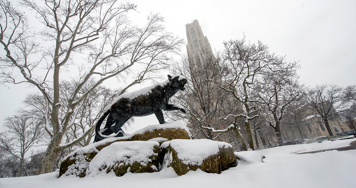 A panther statue in front of the Cathedral of Learning, covered in snow