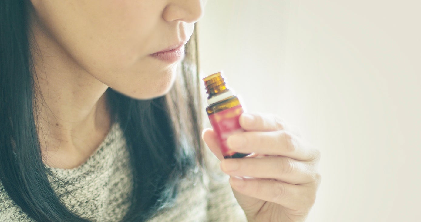 woman holding a small bottle of essential oils to her nose