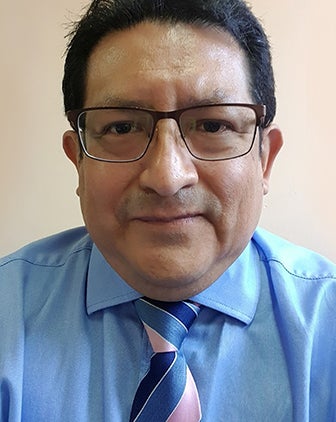 A man with glasses in a blue dress shirt with a striped blue tie