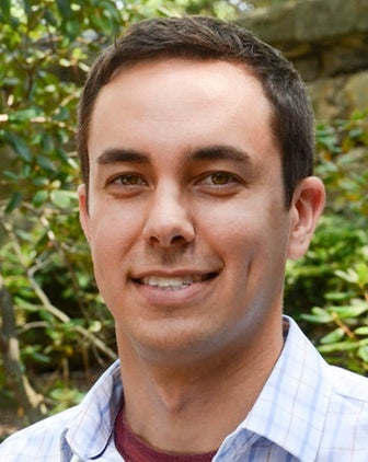 Brian Thoma headshot, with green leafy outdoor background