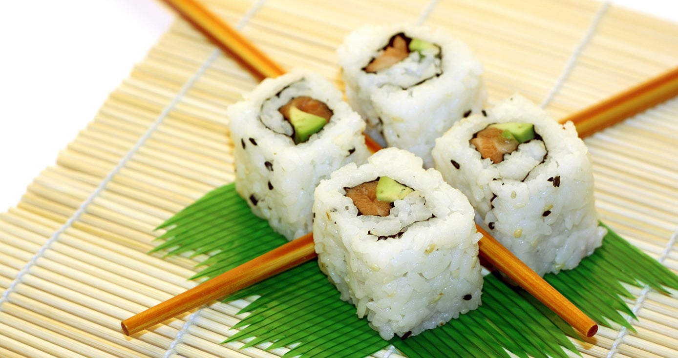 Four rolls of sushi arranged in a square pattern on top of decorative grass