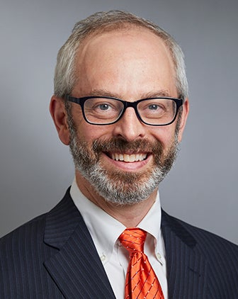 Cary Gross in a dark suit and orange tie