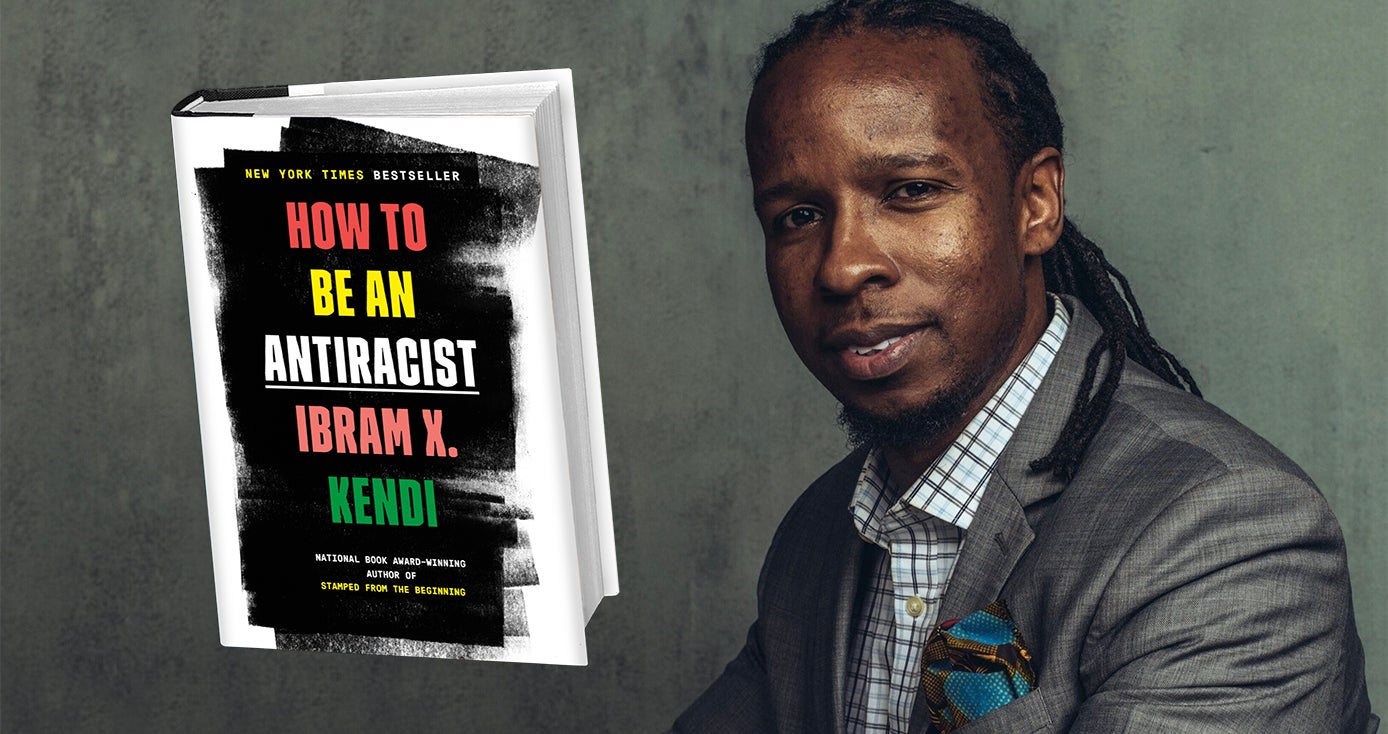Ibram X. Kendi in a gray suit with his book