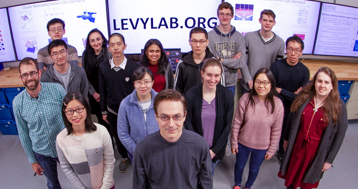 Jeremy Levy, a Distinguished Professor of Condensed Matter Physics in the Department of Physics and Astronomy, stands in front of his team in Levy Lab. 
