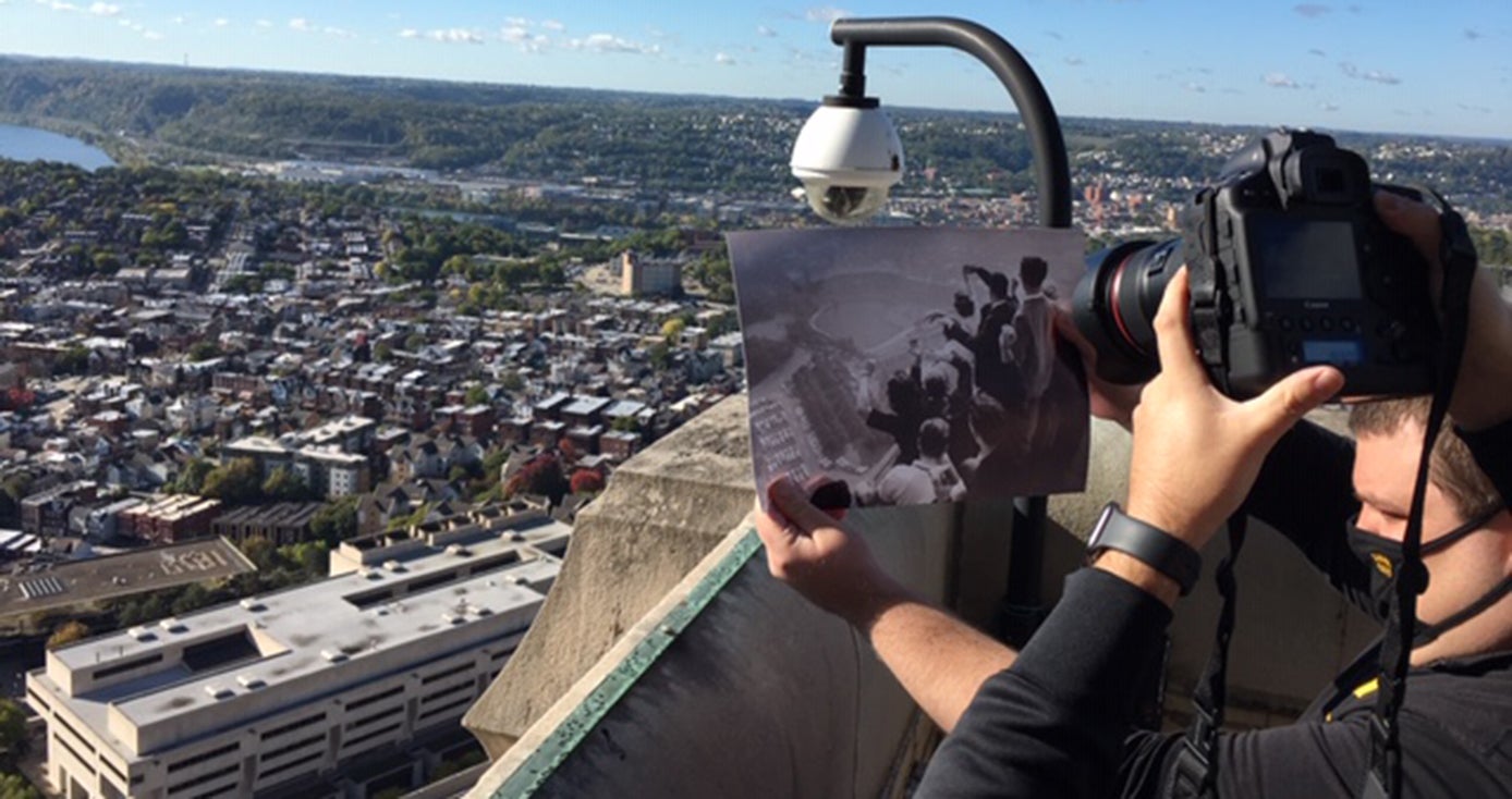 Two people, one holding up a print of the iconic photo and another holding a camera