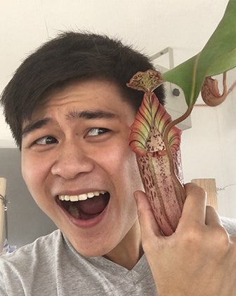 Alvin Liu poses next to a carnivorous plant