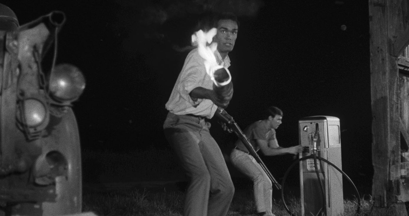 Duane Jones holds a flaming torch in a black and white image