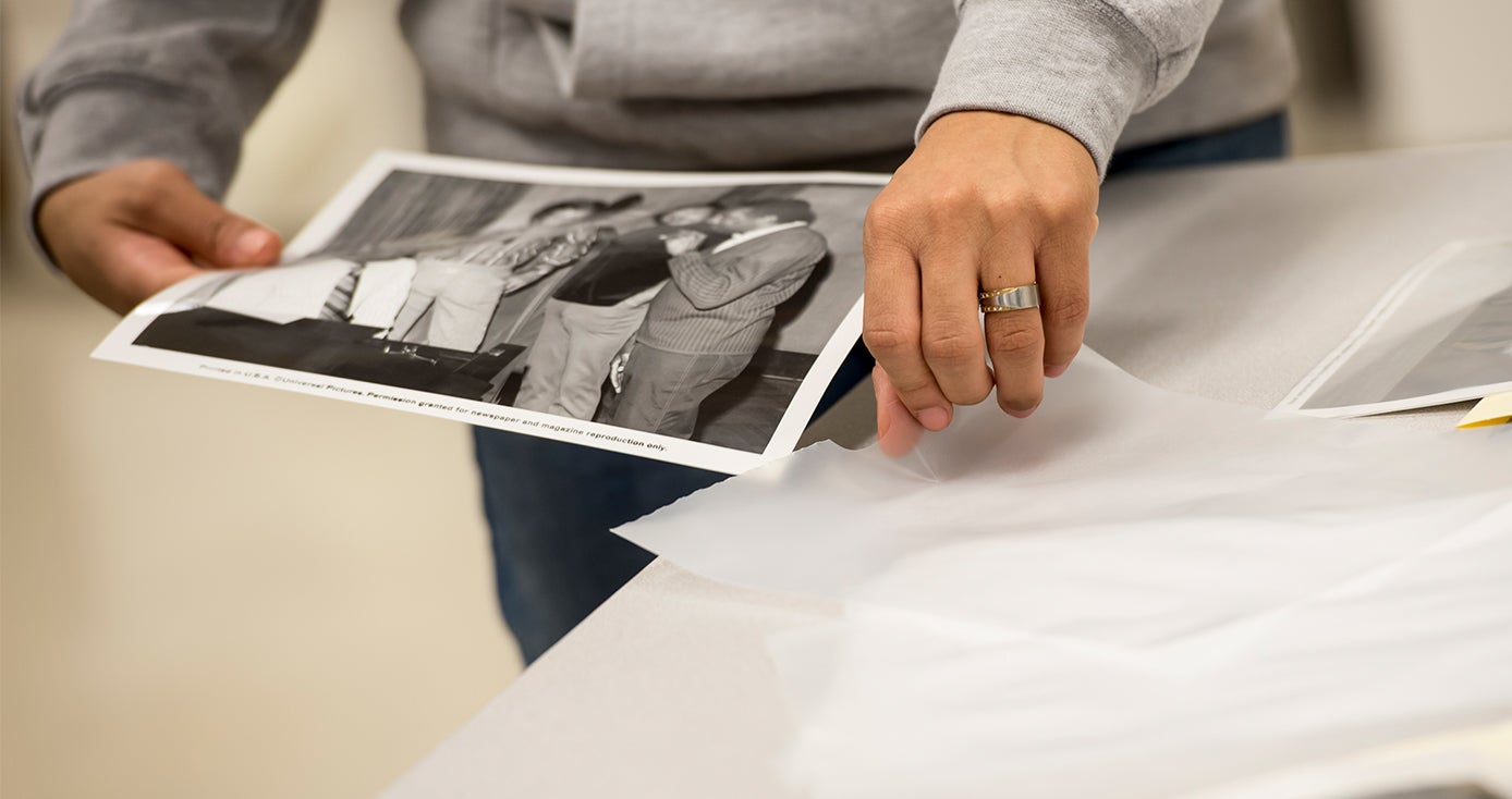 a pair of hands putting a black and white photograph in an envelope