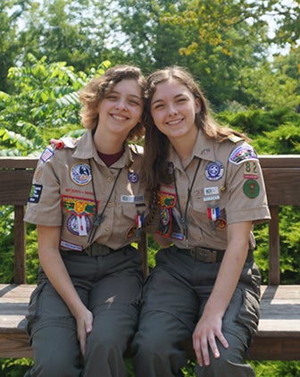 Two women in Scouts uniforms sitting outside