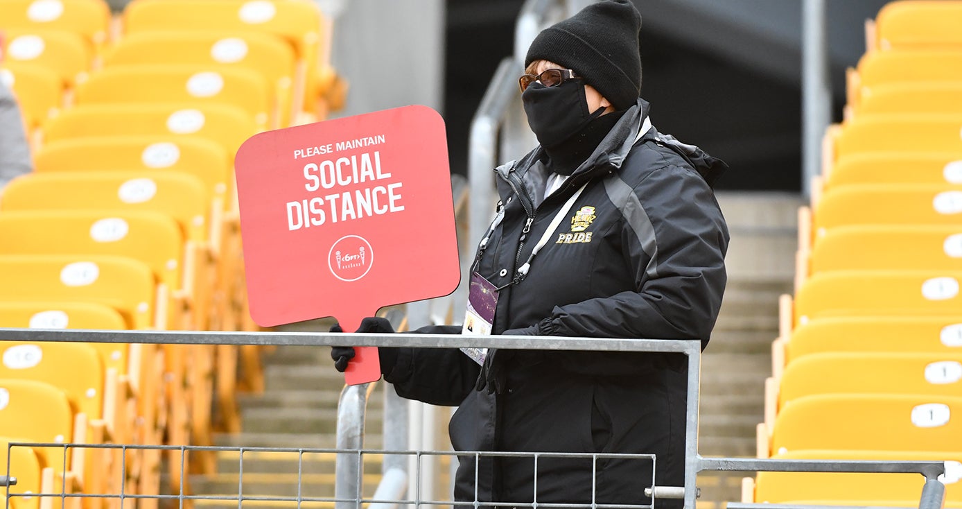 A person in a black face mask holding a red sign