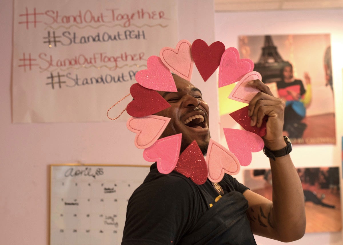 A man beams while placing his face in the middle of paper hearts