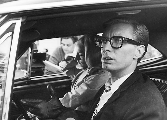 Black and white still image from Night of the Living Dead showing man and woman in front seat of car