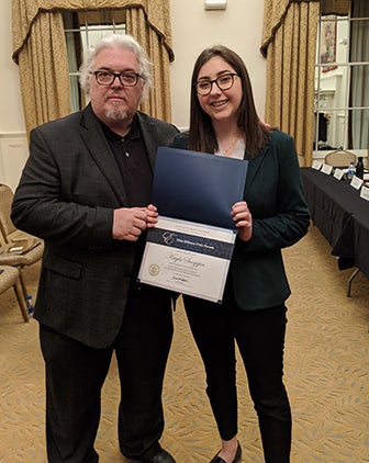 Nello Giorgetti, an adjunct professor teaching the Institute of Politics Internship Seminar, stands beside student Kayla Scoggin as she receives her certificate for completing the program. 