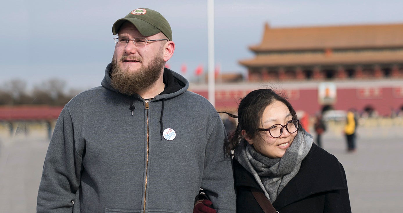 Carl Setzer and Liu Fang outside, wearing cool-weather clothing, in front of a scene in China