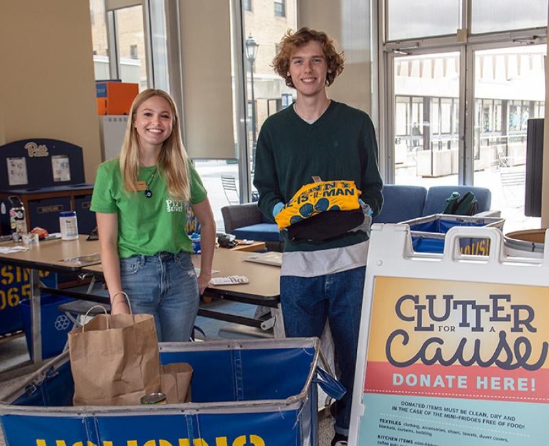 Volunteers stand behind a Clutter for a Cause sign