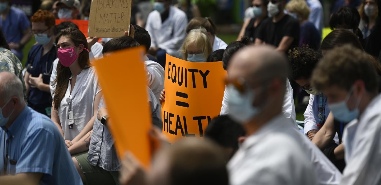 People in masks holding up signs, one saying "Equity = Health"