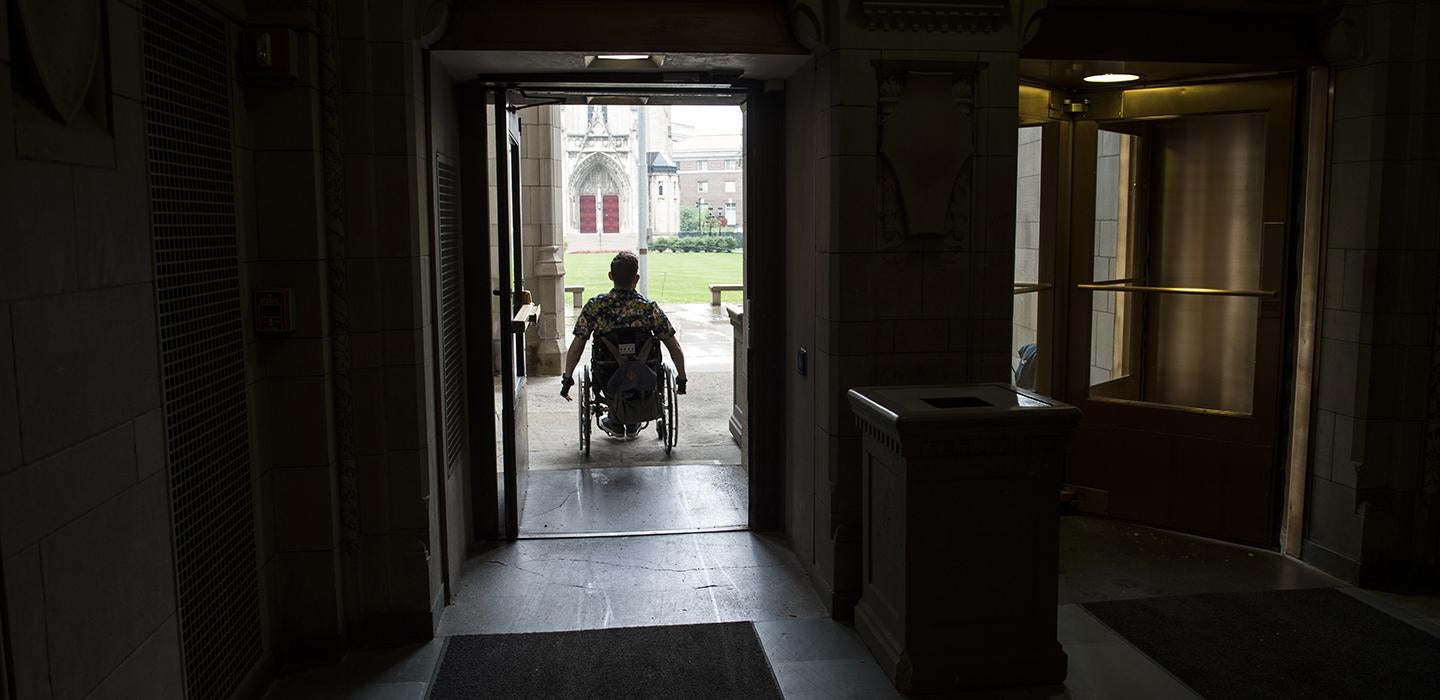 Student with wheelchair going through a doorway
