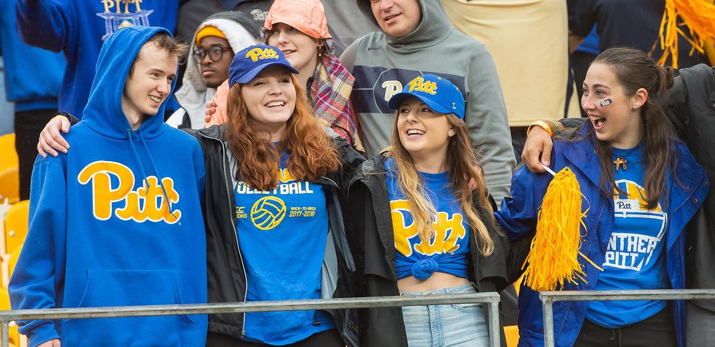 Four students wearing Pitt attire during Homecoming