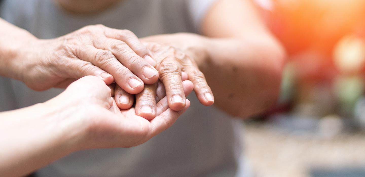 Elderly hands being held by another hand