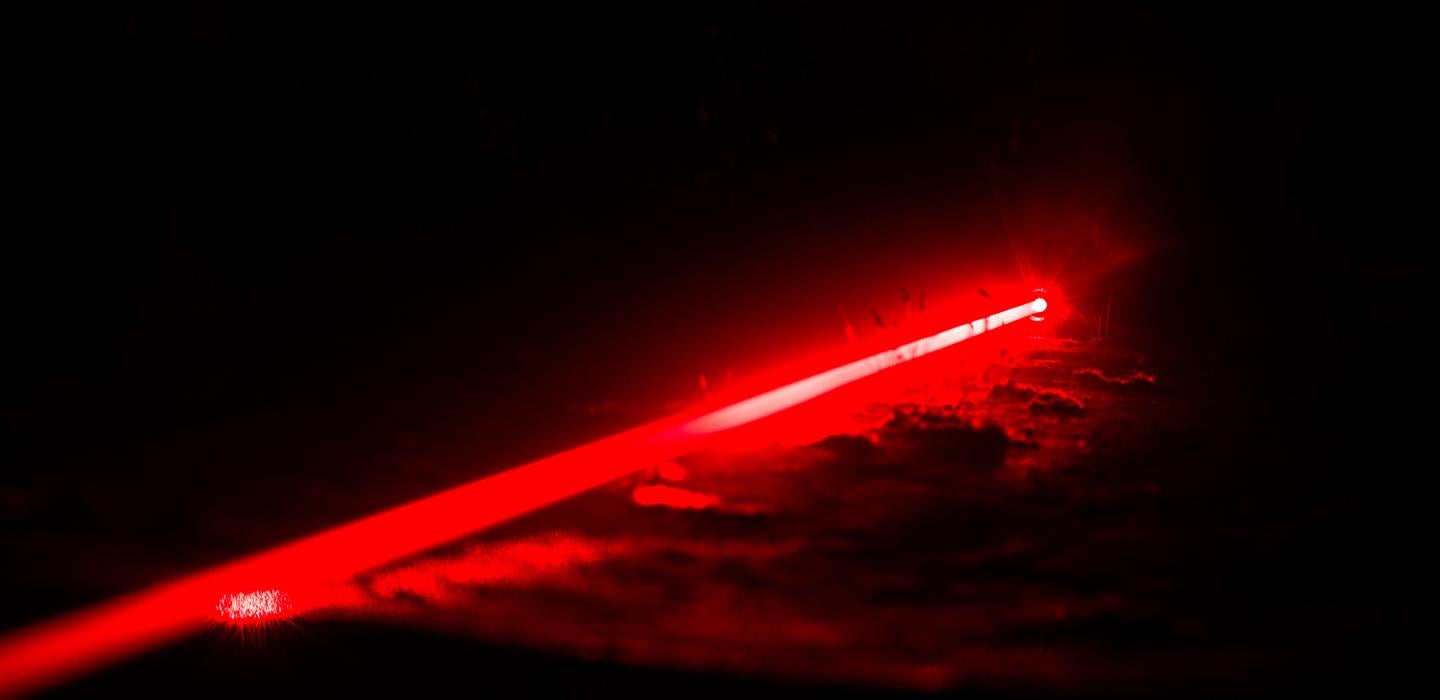 Single red laser beam glowing in dark space
