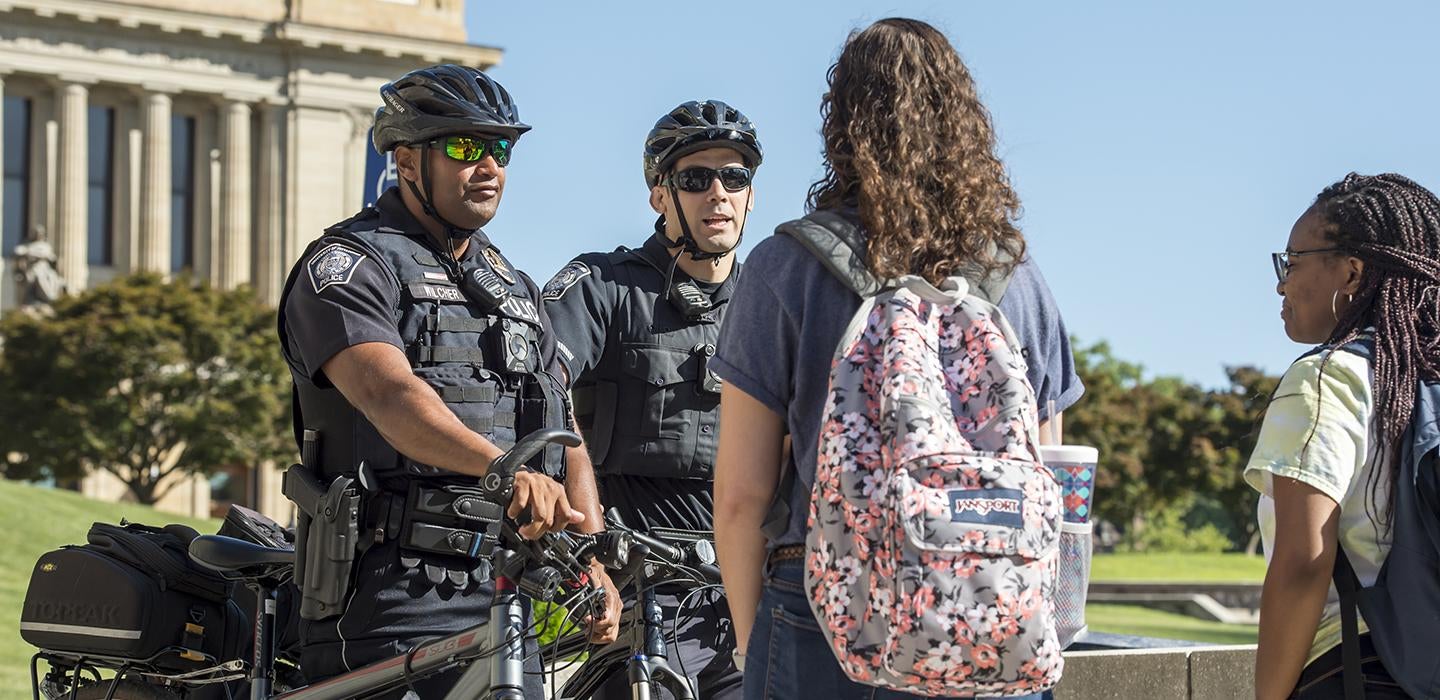 Two police officers talking to students on campus