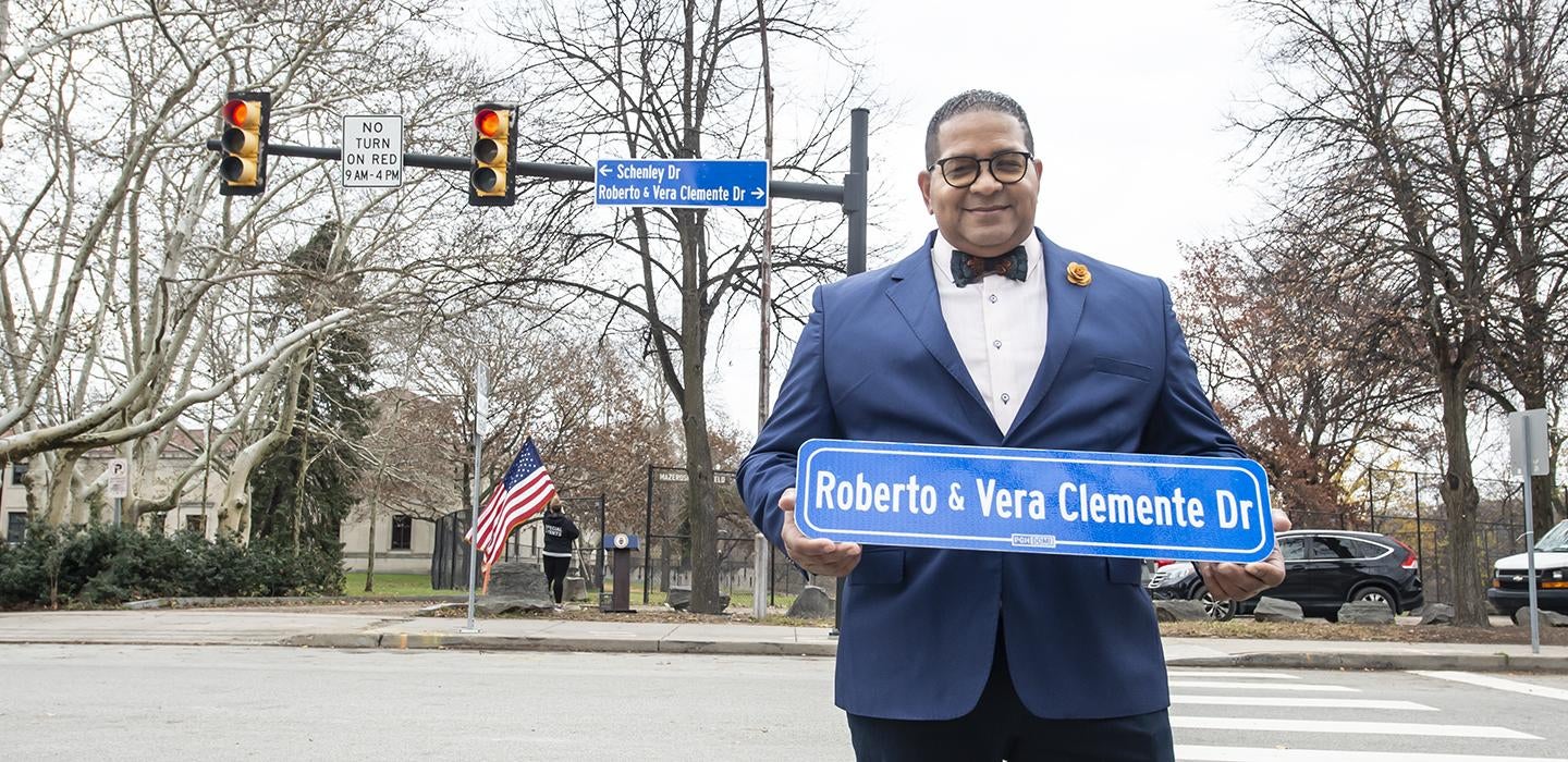 Luis Clemente holding Roberto & Vera Clemente Drive street sign