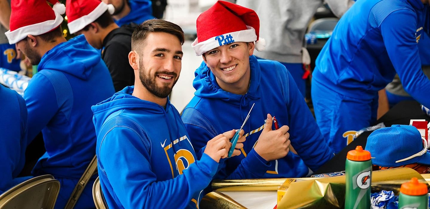 Students wearing Pitt attire and Santa hats with Pitt logo
