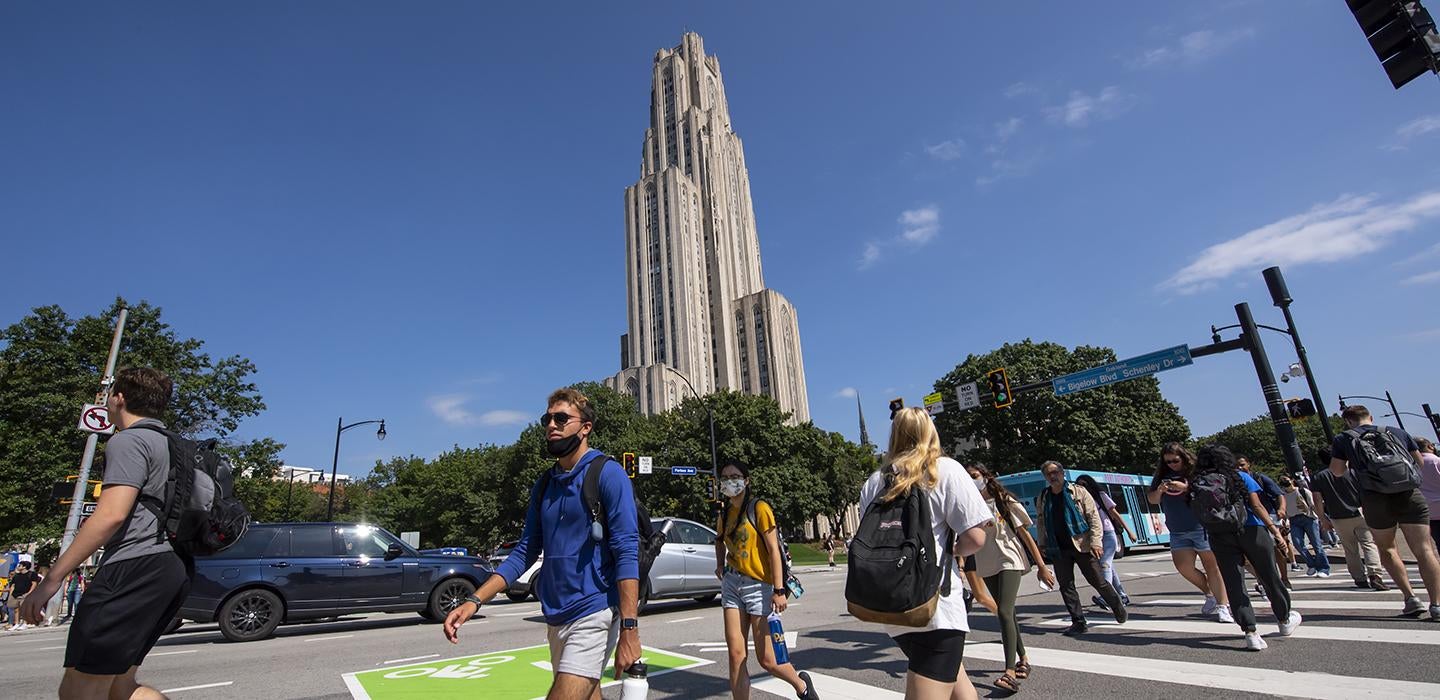 Students crossing a street in front of the Cathedral of Learning
