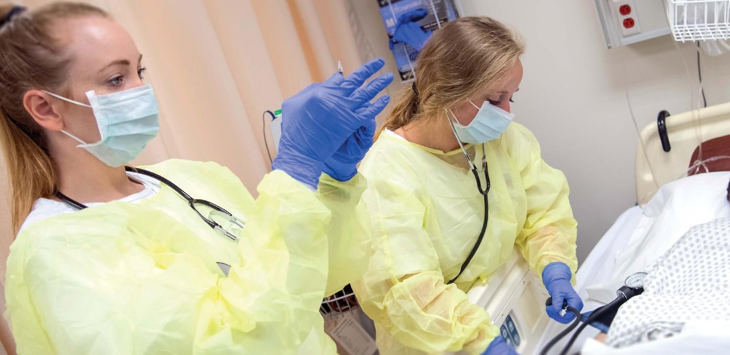 Pitt nurses working together while wearing masks and yellow gowns