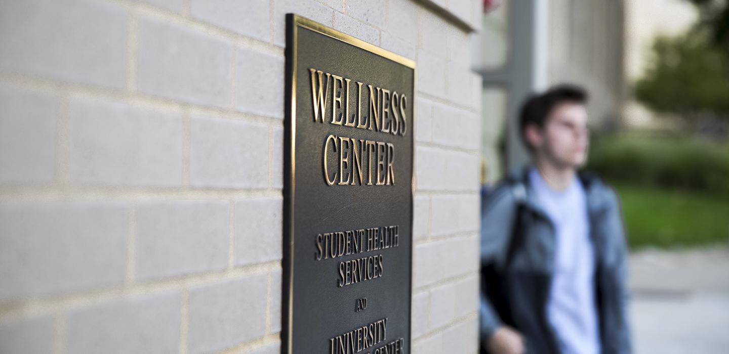 Wellness Center nameplate with person standing next to it