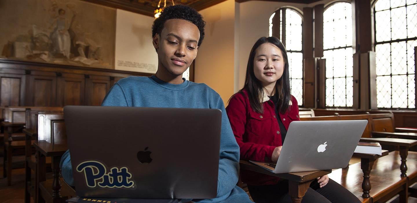 Two students working on laptops in nationality room