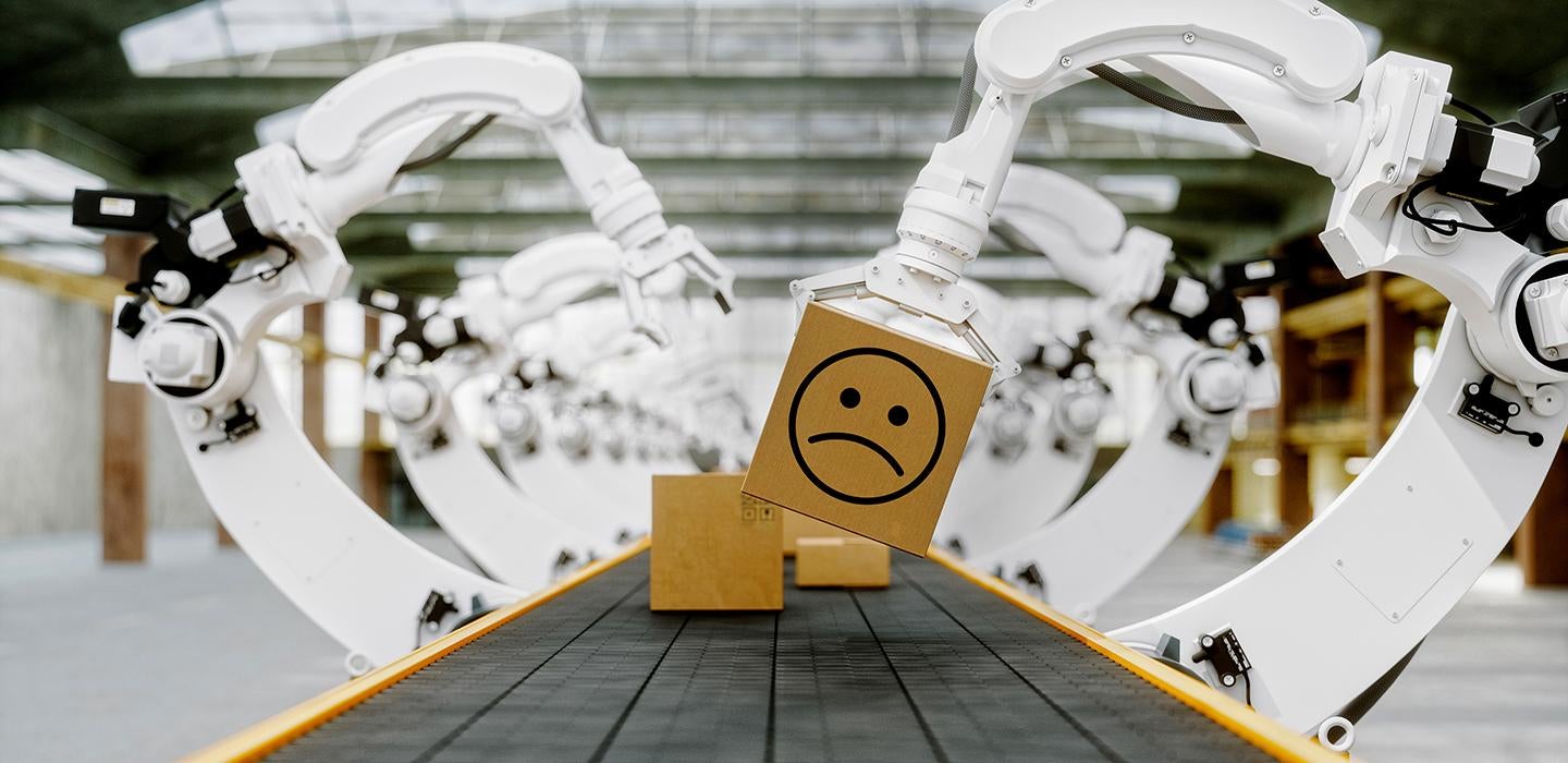 robots on an assembly line picking up a box with a frowny face on it