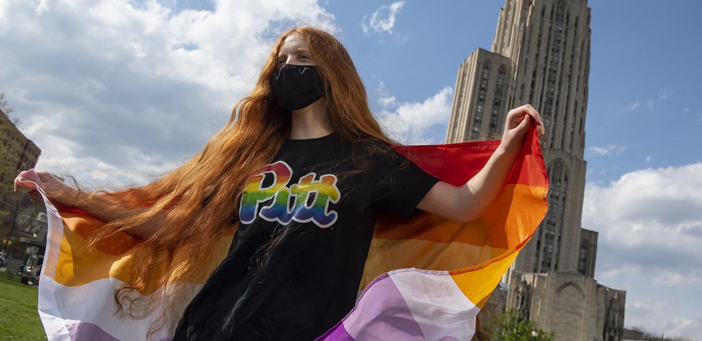 a woman carries a pride flag in front of the cathedral 