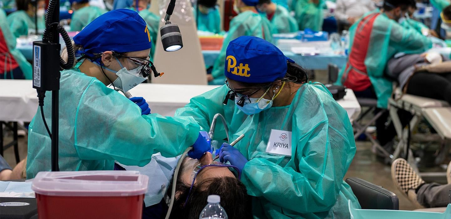 Pitt Dental Medicine folks in scrubs treating a patient