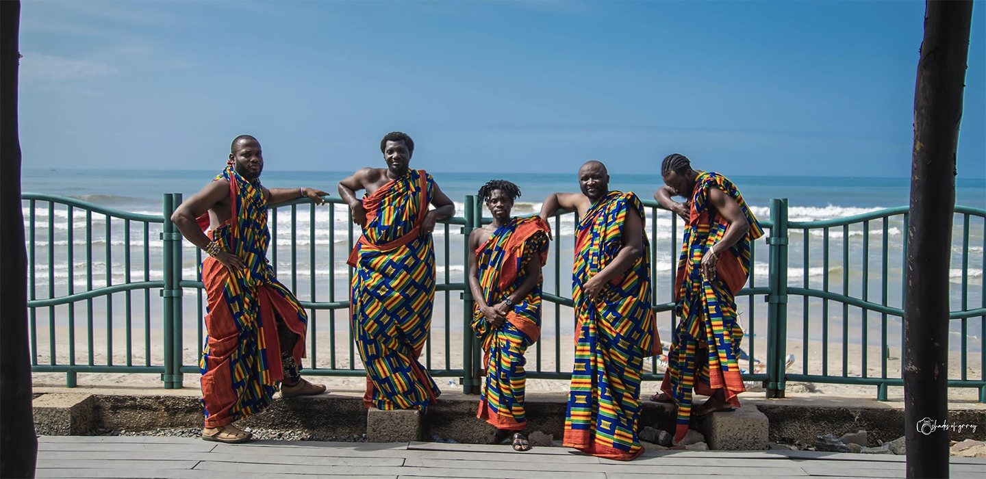 five men in colorful dress on a beach