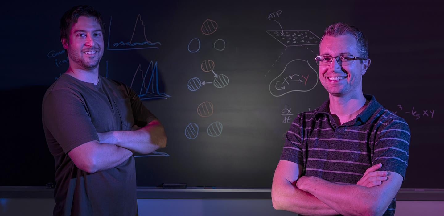 two people lit by magenta light at a chalkboard